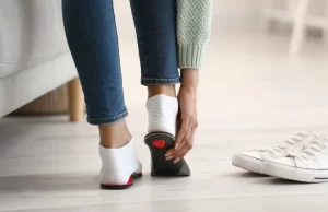 Persona colocándose plantillas personalizadas en sus zapatillas para mejorar la pisada y aliviar el dolor en el día a día