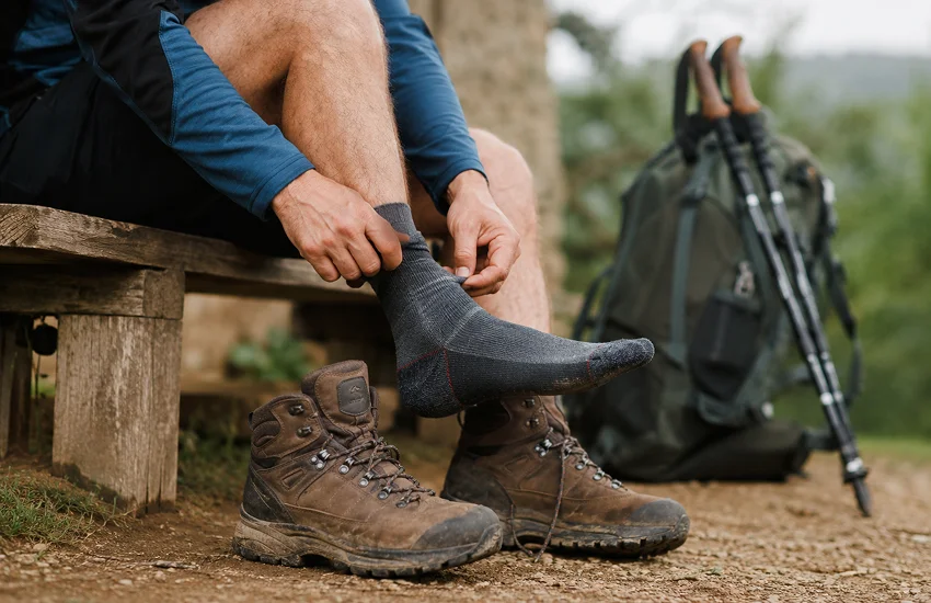 Peregrino revisando el calzado y los calcetines para prevenir molestias en los pies durante el camino de Santiago.